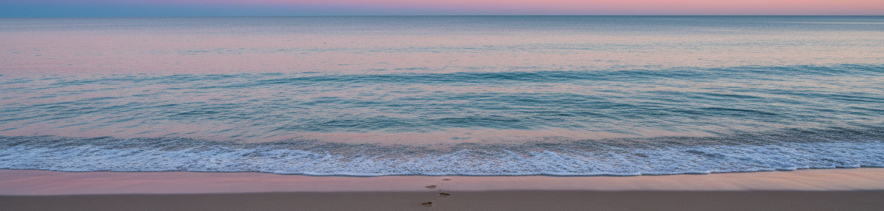 image of the ocean and a beautiful pink and blue sky. with footprints of the beach